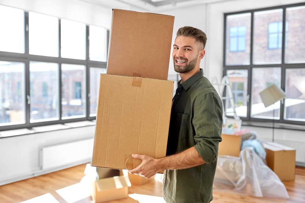 moving, people and real estate concept - happy smiling man holding boxes with stuff at new home. happy man with boxes moving to new home