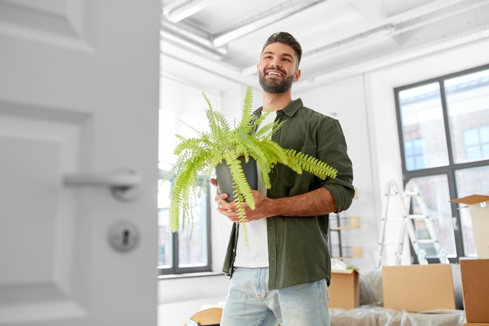 moving, people and real estate concept - happy smiling man with fern flower at new home. happy man with fern flower and moving to new home