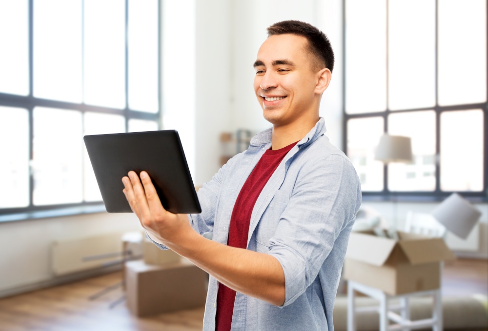 moving, real estate and people concept - happy young man tablet computer over new home background. happy young man with tablet computer over new home