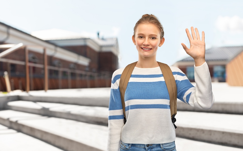 education, travel and tourism concept - happy smiling teenage student girl with school bag or backpack waving hand over city street background. smiling teenage student girl with school bag