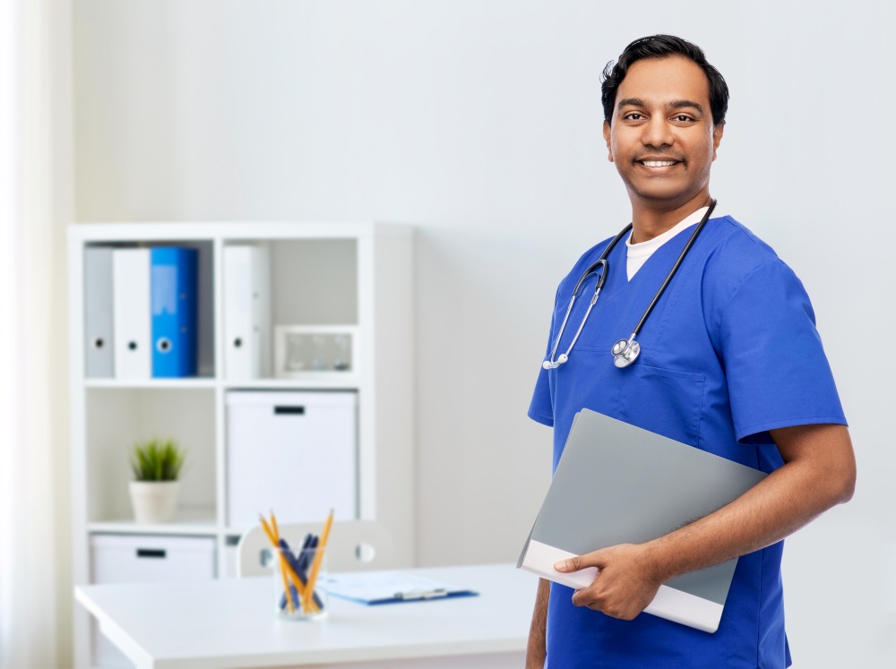 healthcare, profession and medicine concept - happy smiling indian doctor or male nurse in blue uniform with folder and stethoscope report over medical office at hospital background. happy indian doctor with folder and stethoscope