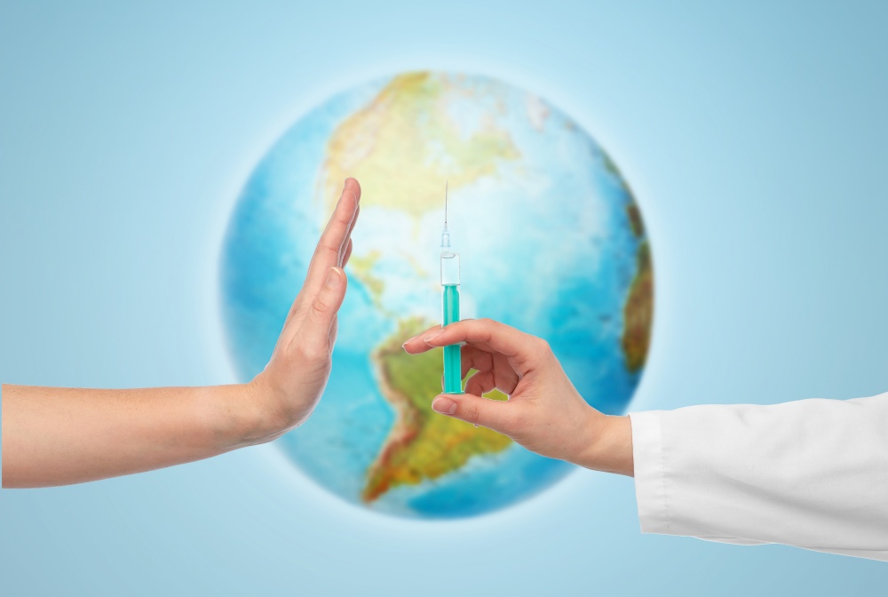 medicine, vaccination and healthcare concept - hand of doctor with syringe and patient showing stop gesture over earth globe on blue background. hand with syringe and showing stop gesture
