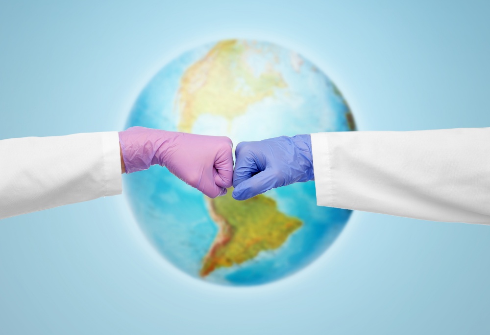 medicine, health protection and healthcare concept - hands of doctors in gloves make fist bump gesture over earth globe on blue background. hands of doctors in gloves make fist bump gesture