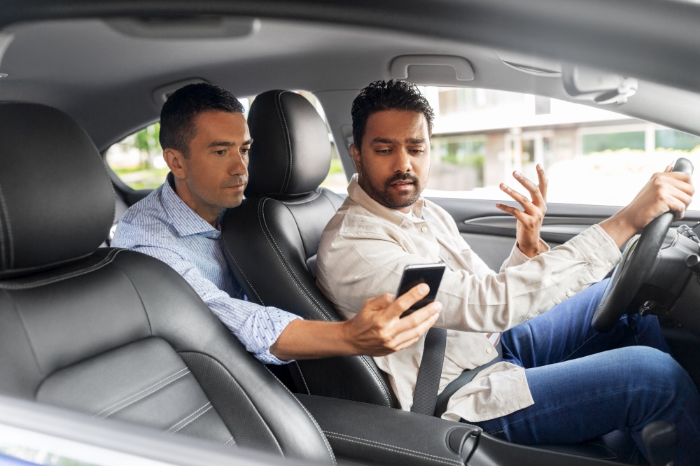 transportation, vehicle and technology concept - male passenger showing smartphone to car driver. male passenger showing smartphone to car driver