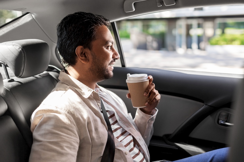 transport, business and people concept - happy smiling indian man with takeaway coffee on back seat in taxi car. indian man with takeaway coffee on car back seat