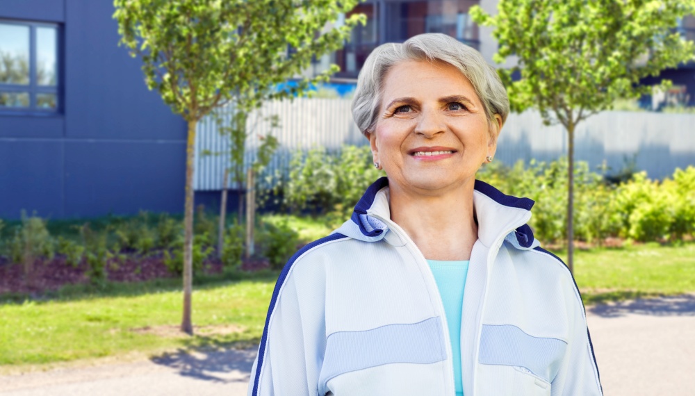 fitness, sport and healthy lifestyle concept - smiling sporty senior woman over city street background. smiling sporty senior woman in city