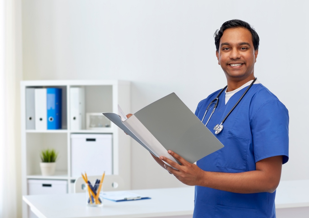 healthcare, profession and medicine concept - happy smiling indian doctor or male nurse in blue uniform with folder report over medical office at hospital background. happy indian doctor with medical report in folder