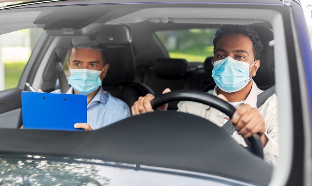 driver courses, health and people concept - young man and driving school instructor in mask with clipboard in car. car driving school instructor and driver in mask