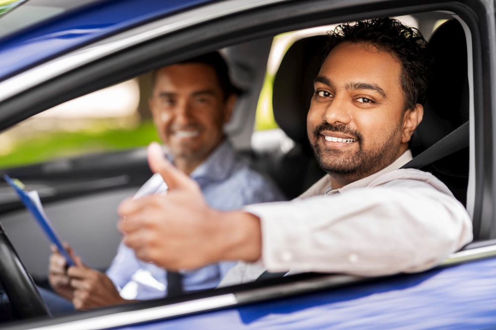 driver courses, exam and people concept - happy smiling indian man showing thumbs up and driving school instructor with clipboard in car. smiling driver and car driving school instructor