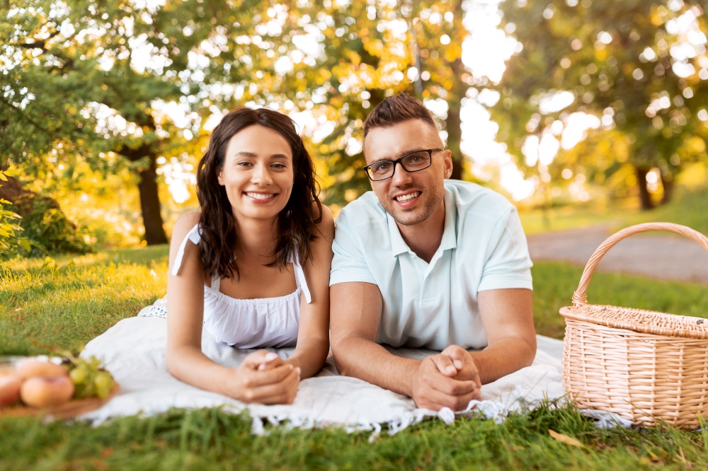 leisure, vacation and people concept - happy couple lying on picnic blanket at summer park. happy couple on picnic blanket at summer park