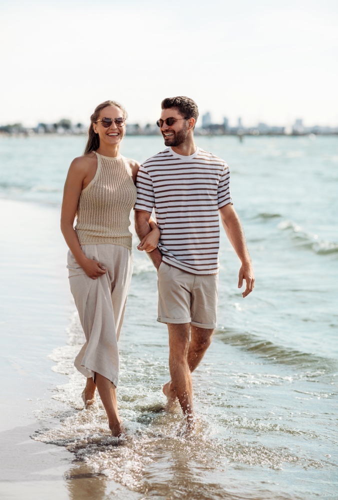 summer holidays and people concept - happy couple walking along beach. happy couple walking along summer beach