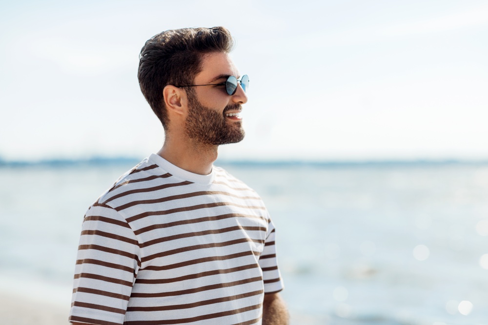 summer holidays and people concept - portrait of happy smiling young man in sunglasses on beach. smiling young man in sunglasses on summer beach