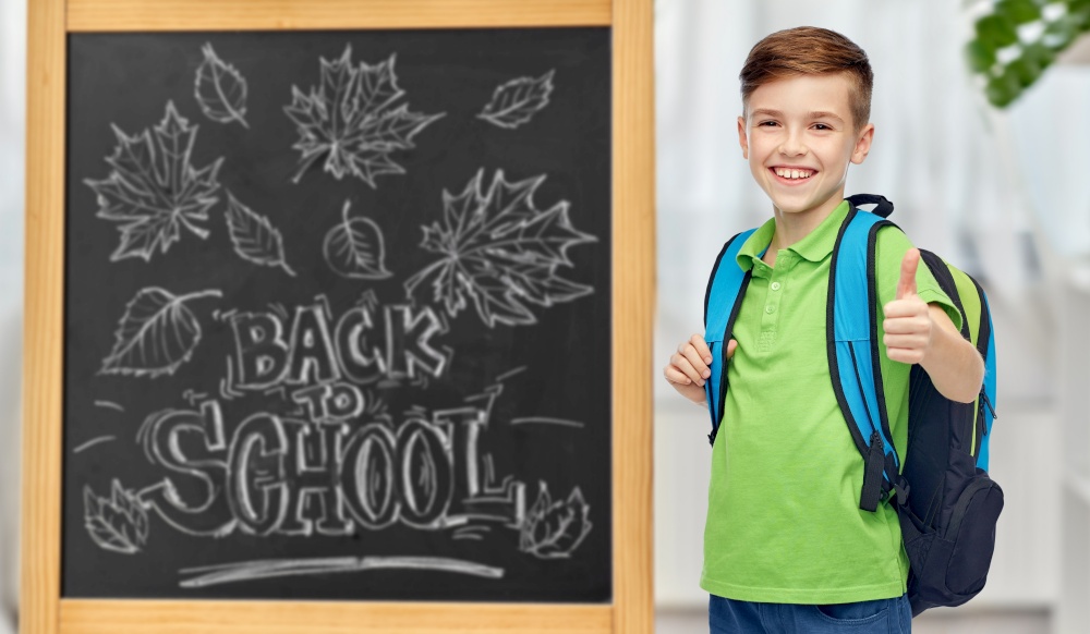 education, learning and people concept - happy smiling student boy with school bag over chalkboard with back to school lettering on background. happy student boy with school bag over chalkboard