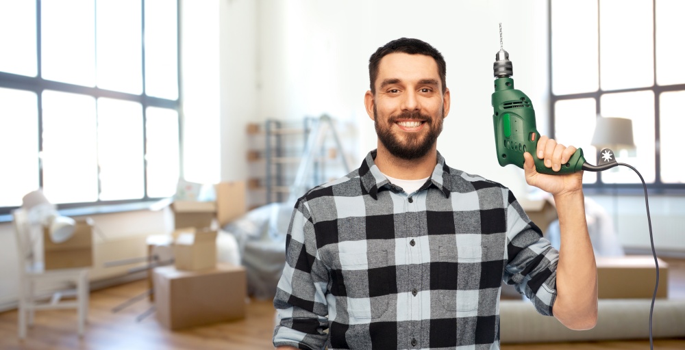 repair, construction and building concept - happy smiling man, worker or builder with drill over home room background. happy man, worker or builder with drill at home