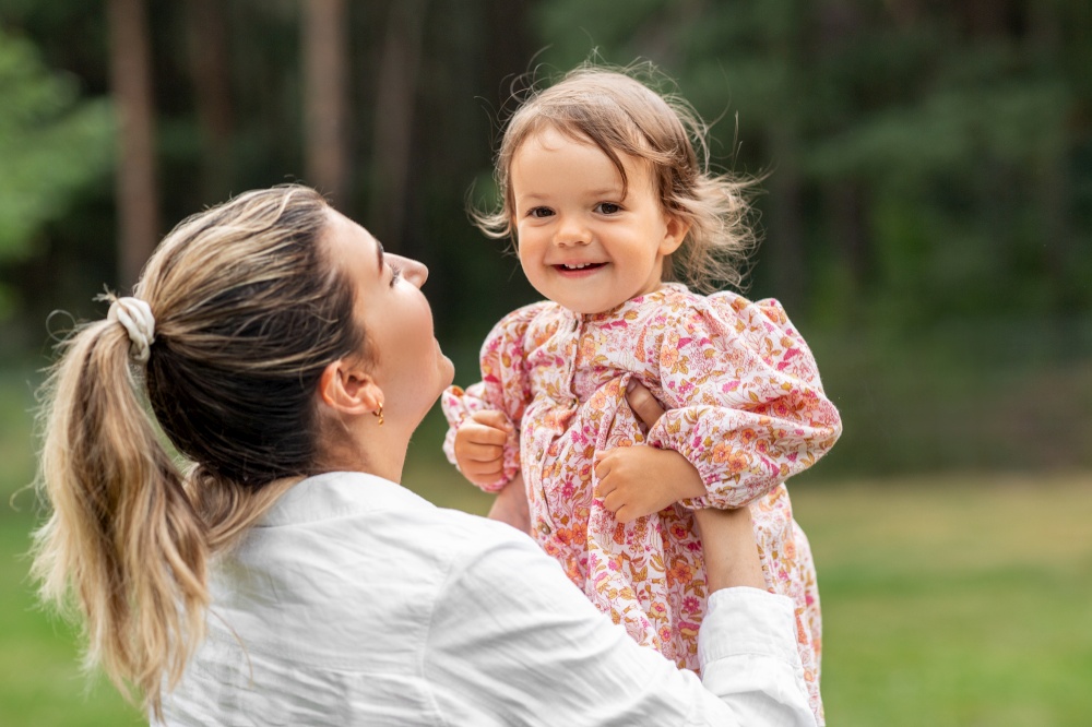 family, motherhood and people concept - happy smiling mother holding little baby girl outdoors. happy smiling mother with baby girl outdoors