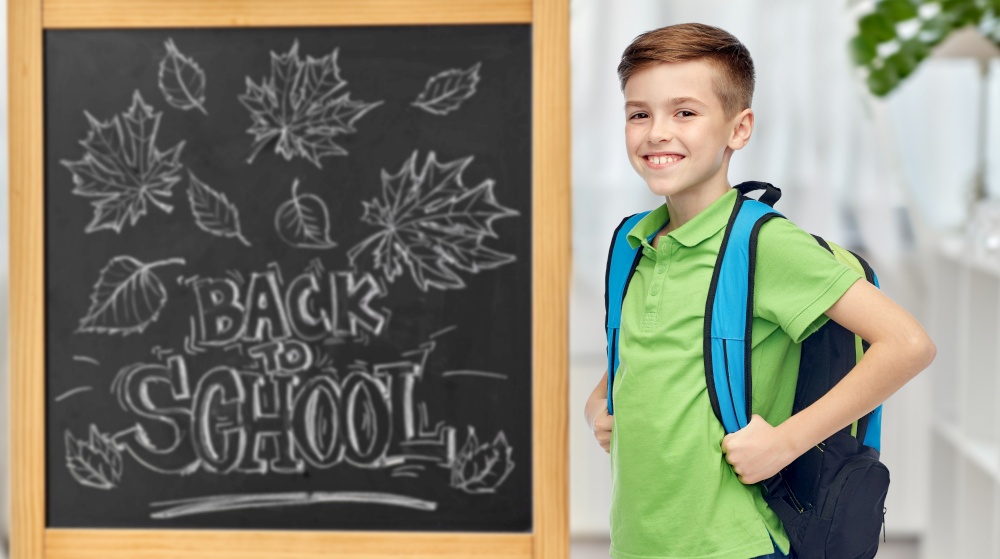 education, learning and people concept - happy smiling student boy with bag over chalkboard with back to school lettering on background. happy student boy with school bag