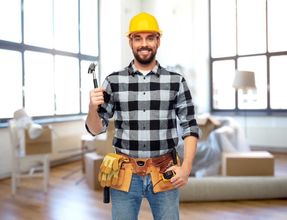 repair, construction and building concept - happy smiling male worker or builder in helmet with hammer over home room background. happy male builder in helmet with hammer at home