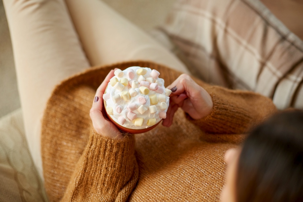 food and leisure concept - close up of woman holding mug of marshmallow and whipped cream. woman holding mug of marshmallow and whipped cream