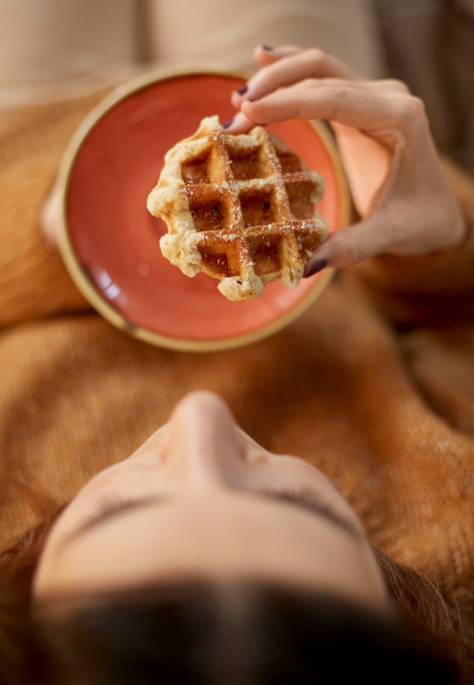food, season and leisure concept - close up of woman eating waffle at home. close up of woman eating waffle at home
