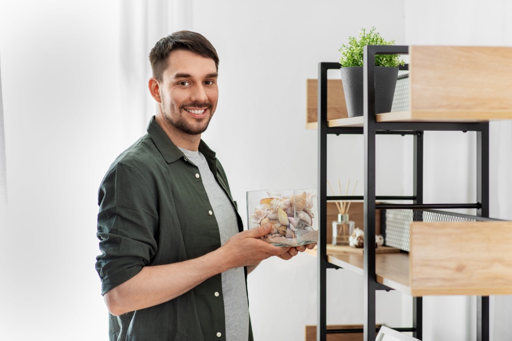 home improvement and decoration and people concept - woman placing seashells in vase to shelf. man decorating home with seashells in vase