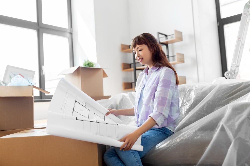 moving, people and real estate concept - happy smiling asian woman with blueprint and boxes at new home. woman with blueprint and boxes moving to new home