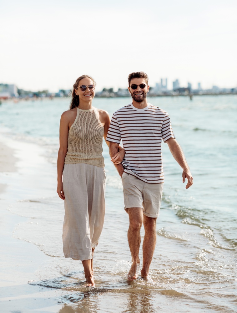 summer holidays and people concept - happy couple walking along beach. happy couple walking along summer beach