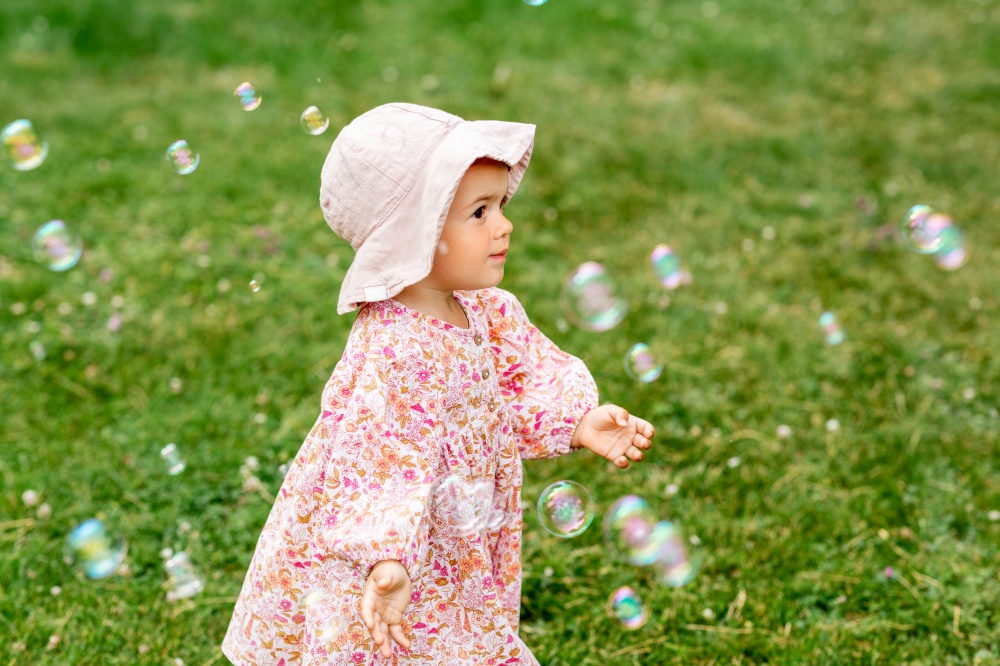 childhood, leisure and people concept - happy little baby girl playing with soap bubbles in summer. happy baby girl playing with soap bubbles outdoors