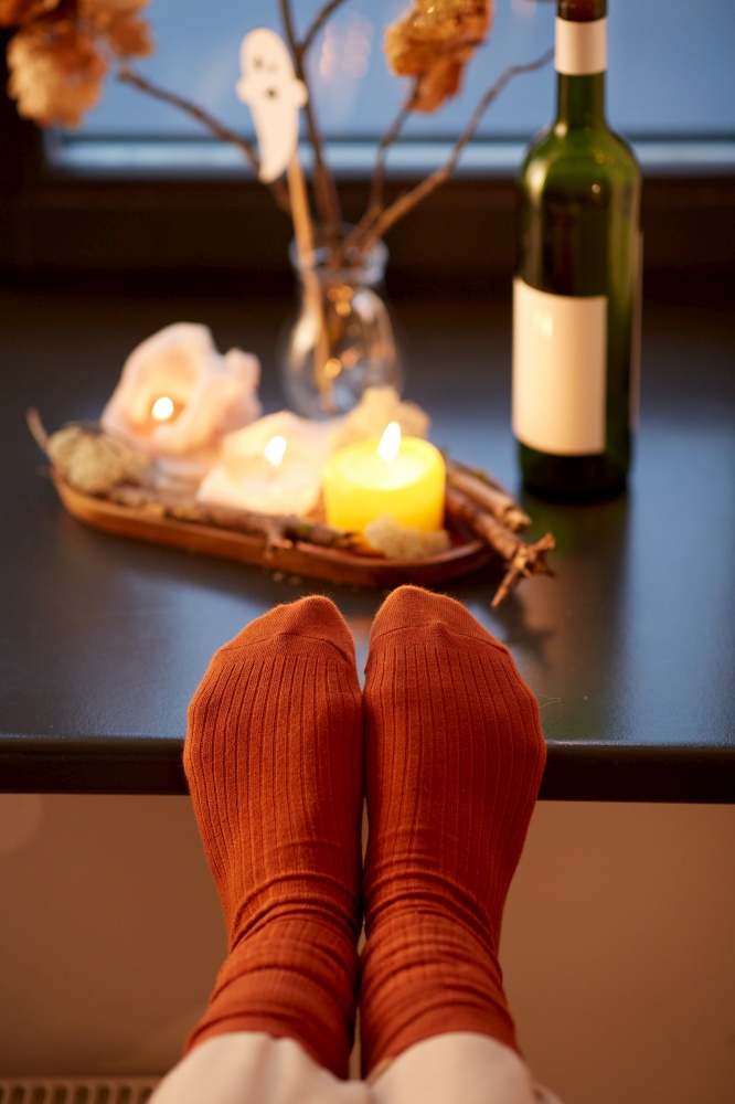 halloween, hygge and leisure concept - feet in socks on window sill at home in autumn. feet in socks on window sill at home in autumn