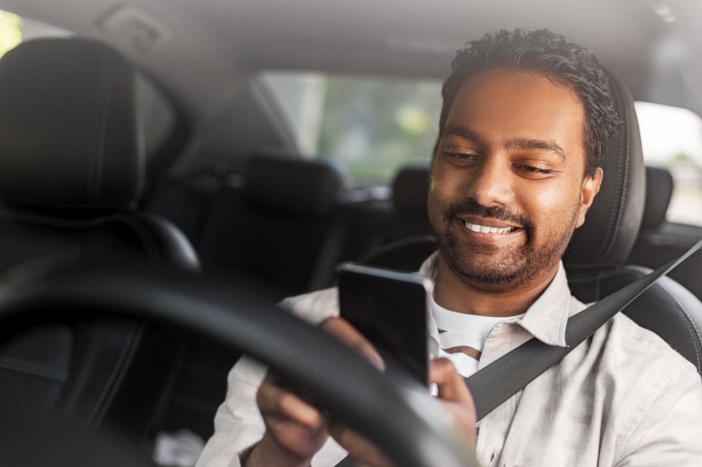 transport, people and technology concept - smiling indian man or driver using smartphone in car. smiling indian man in car using smartphone