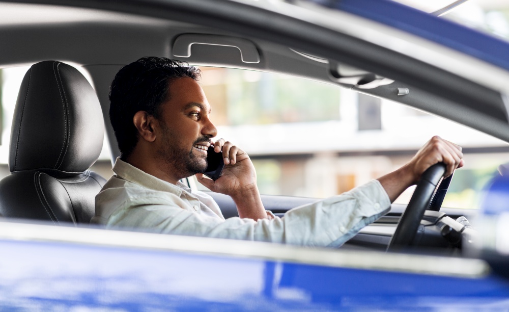 transport, communication and people concept - smiling indian man or driver driving car and calling on smartphone. indian man driving car and calling on smartphone