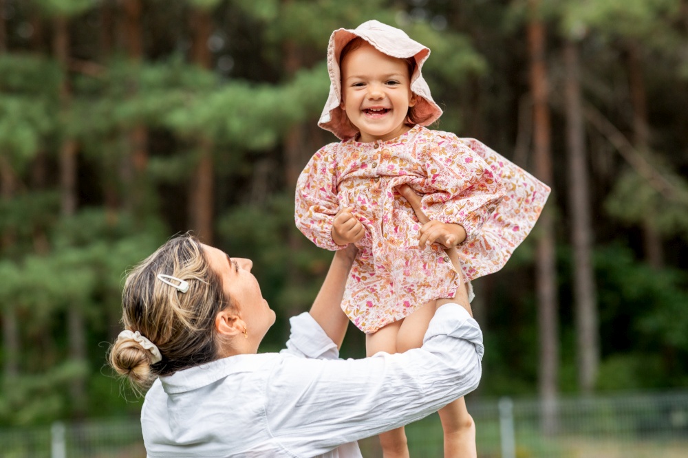 family, motherhood and people concept - happy smiling mother holding little baby girl outdoors. happy smiling mother with baby girl outdoors
