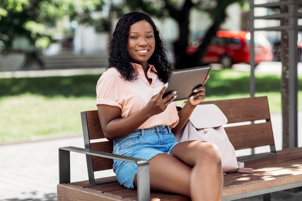 technology, lifestyle and people concept - happy smiling african american woman with tablet pc computer in city. african american woman with tablet pc in city