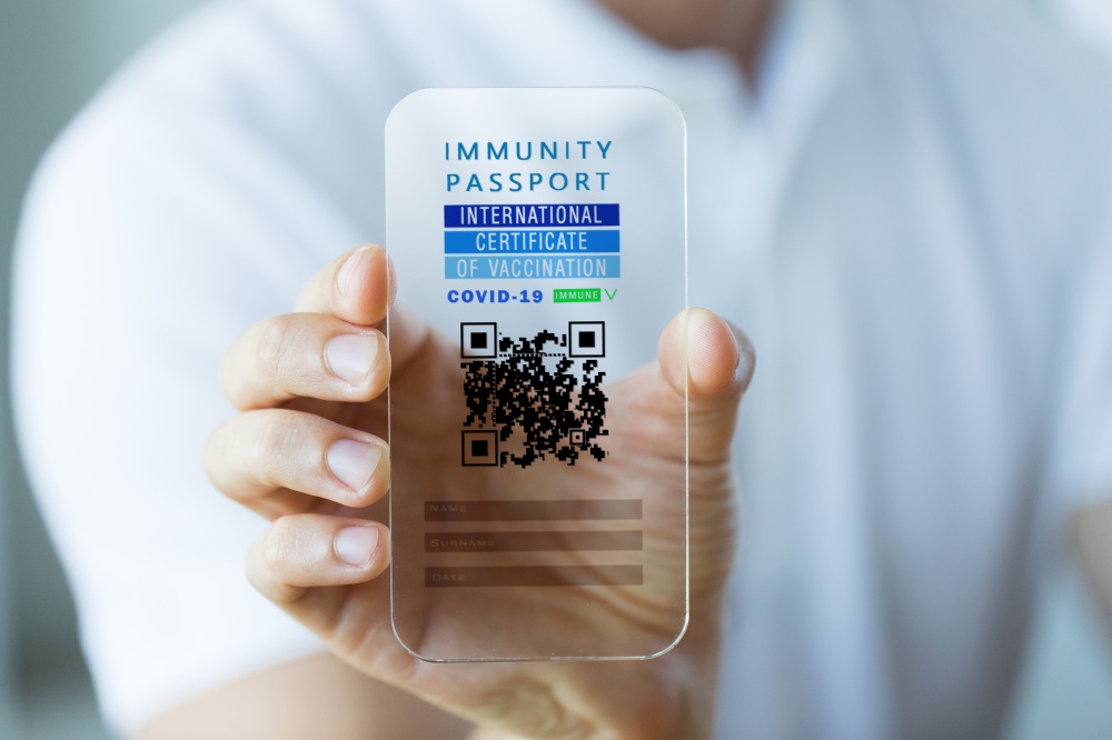 technology and health care concept - close up of man&rsquo;s hand holding transparent smartphone with virtual immunity passport or international certificate of vaccination on screen. hand with virtual immunity passport on smartphone