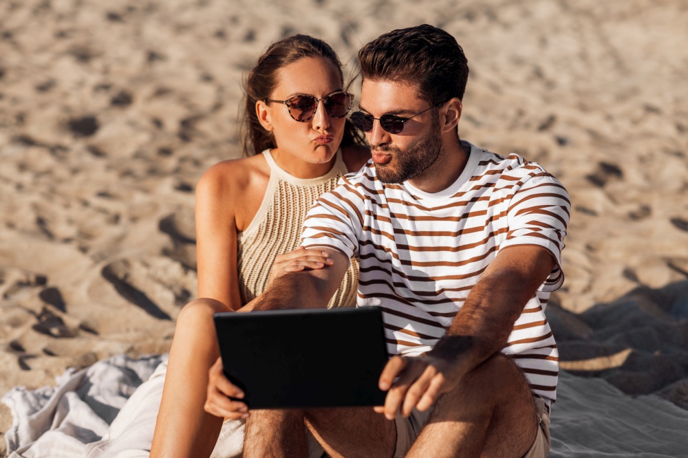 leisure and people concept - happy couple with tablet pc computer on summer beach. happy couple with tablet pc at on summer beach