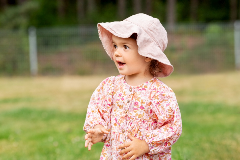 childhood, leisure and people concept - happy little baby girl in panama hat outdoors in summer. happy little baby girl outdoors in summer