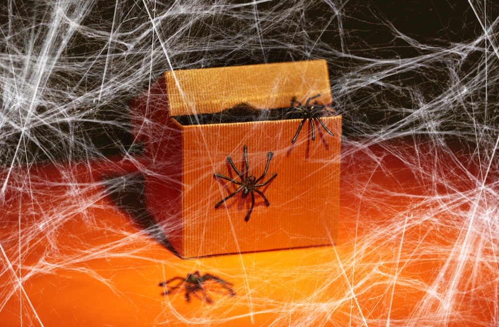 halloween, holidays and party concept - toy spiders crawling out of gift box and spiderweb over dark background. toy spiders crawling out of gift box on halloween