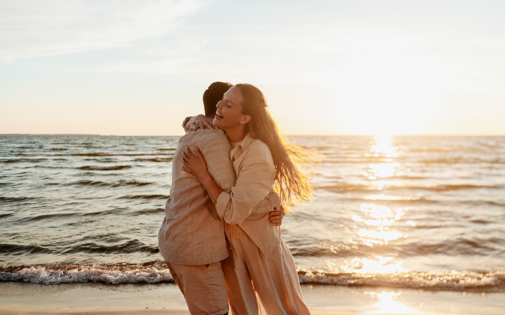 leisure, relationships and people concept - happy couple hugging on summer beach. happy couple hugging on summer beach