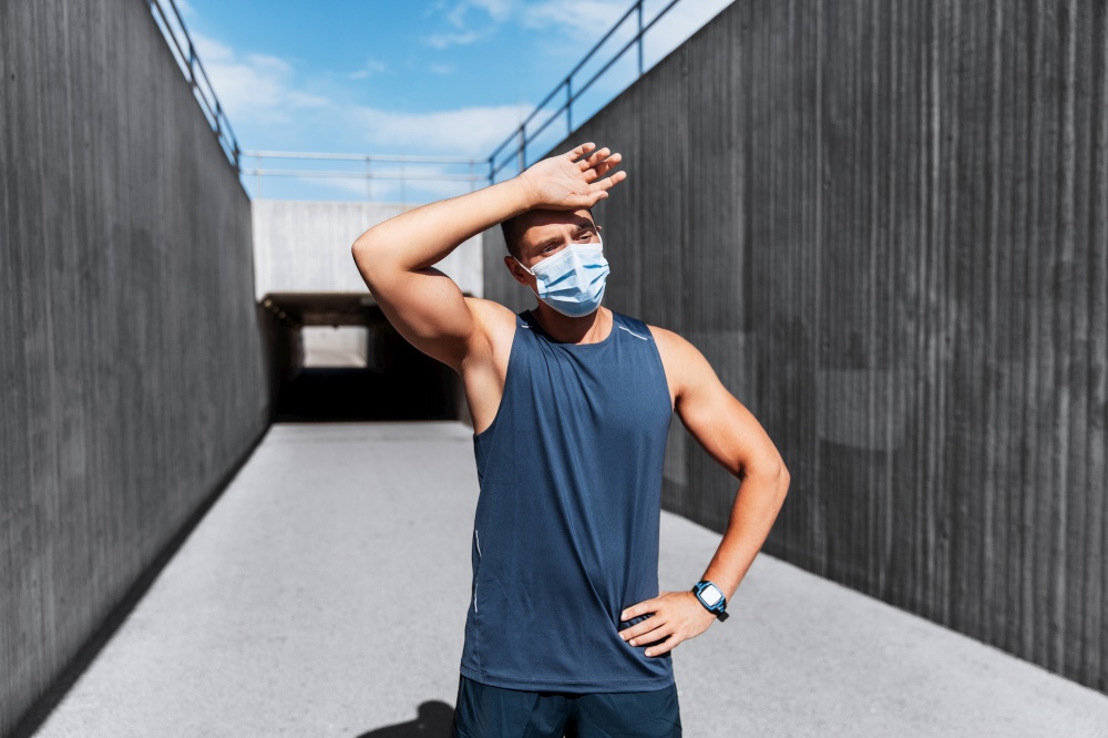 fitness, sport and health concept - tired young man in medical mask doing sports outdoors. tired man in medical mask doing sports outdoors