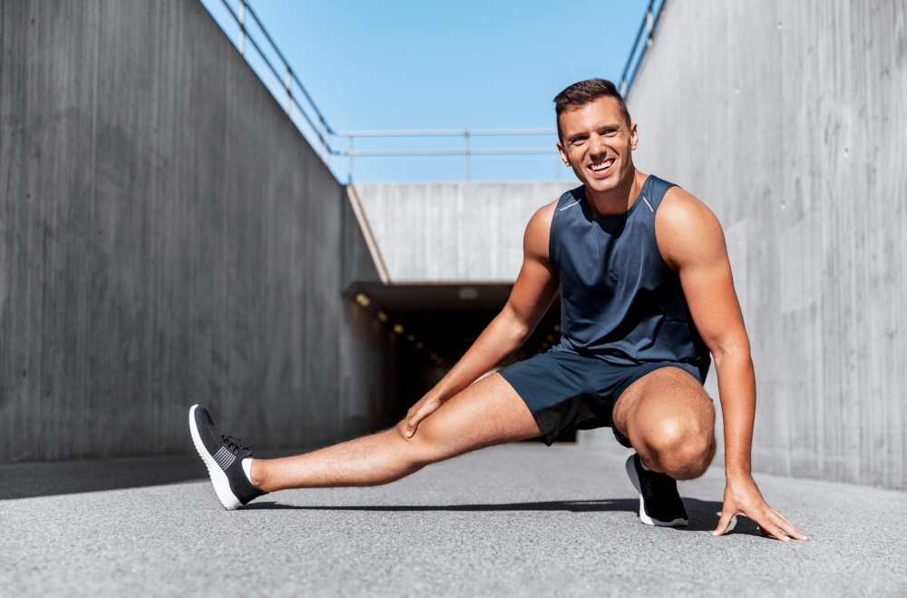 fitness, sport and healthy lifestyle concept - man exercising and stretching leg outdoors. man doing sports and stretching leg outdoors