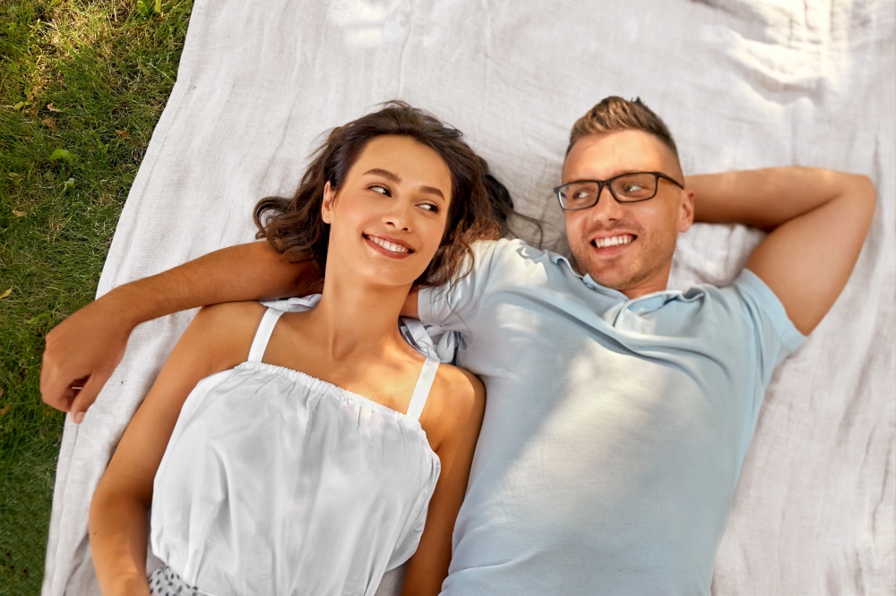 leisure, vacation and people concept - happy couple lying on picnic blanket. happy couple on picnic blanket