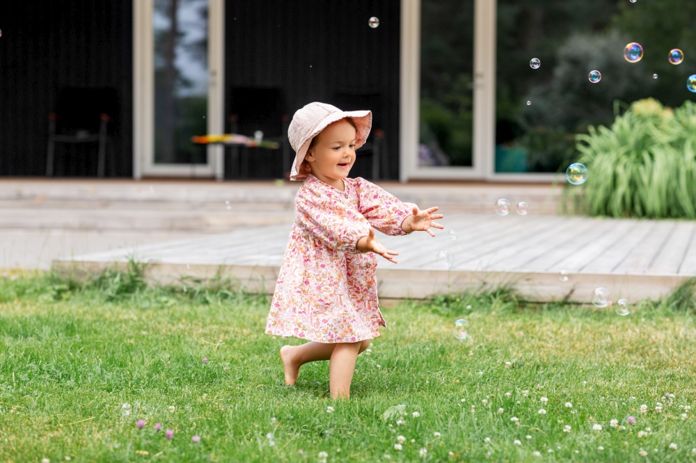 childhood, leisure and people concept - happy little baby girl playing with soap bubbles in summer. happy baby girl playing with soap bubbles outdoors
