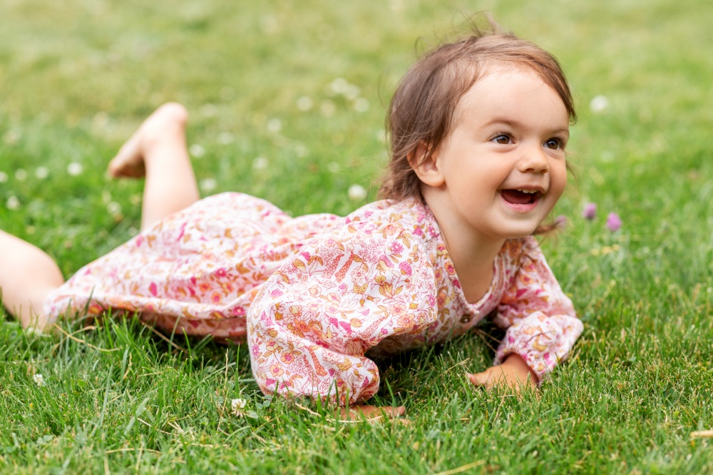 childhood, leisure and people concept - happy smiling little baby girl lying on grass in summer. happy little baby girl lying on grass in summer