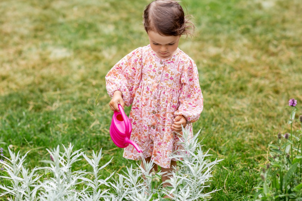 childhood, leisure and people concept - happy little baby girl with watering can in summer garden. happy baby girl with watering can in summer garden
