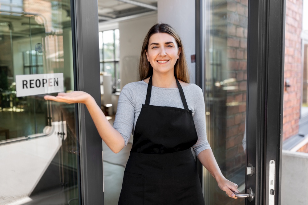 small business, reopening and service concept - happy smiling woman showing reopen banner on window or door glass. happy woman showing reopen banner on door glass