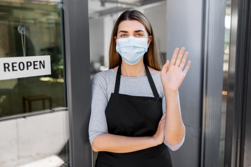 small business, reopening and service concept - woman in mask with reopen banner on window or door glass waving hand. woman in mask with reopen banner on door glass