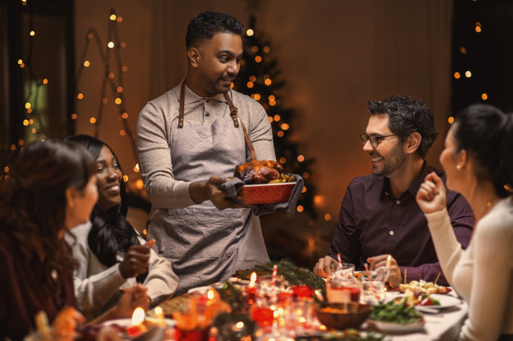 holidays and celebration concept - multiethnic group of happy friends having christmas dinner at home. happy friends having christmas dinner at home