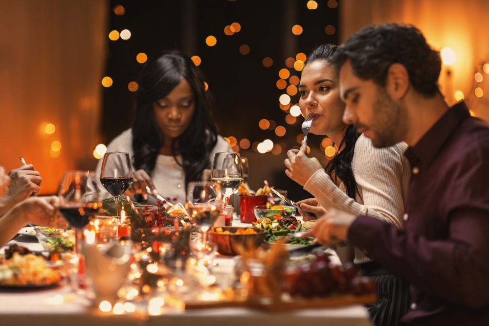 holidays, party and celebration concept - multiethnic group of happy friends having christmas dinner at home. happy friends having christmas dinner at home