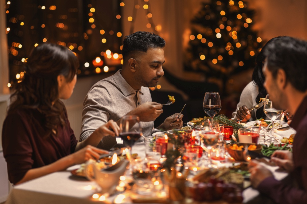 holidays, party and celebration concept - multiethnic group of happy friends having christmas dinner at home. happy friends having christmas dinner at home