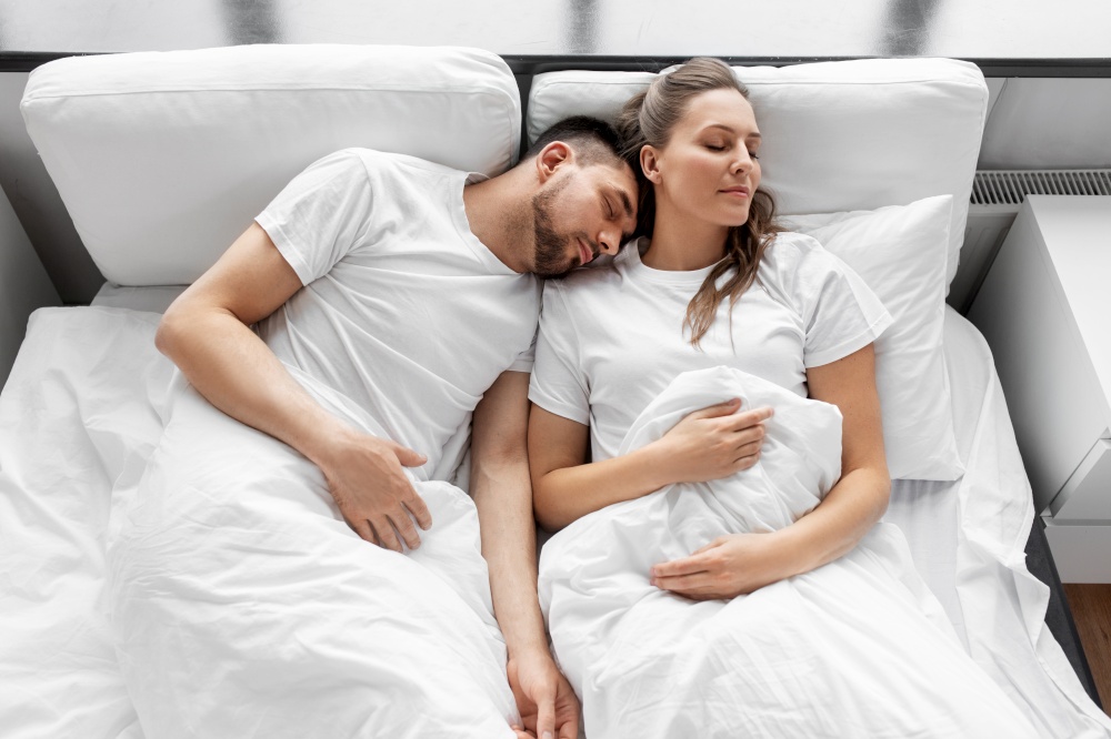 rest and people concept - happy couple sleeping in bed at home. happy couple sleeping in bed at home