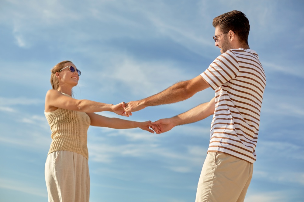 leisure, relationships and people concept - happy couple in sunglasses holding hands outdoors. happy couple holding hands outdoors